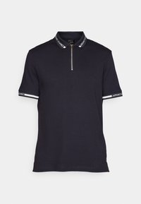 Polo marine à col zippé. Présente des accents rayés sur les manches et une bande logo au niveau du col, fabriqué en tissu lisse.