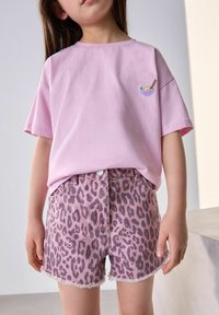 Ruži�časta pamučna majica s kratkim rukavima i malim izvezenim dizajnom zdjele, u kombinaciji s ružičastim trapericama s leopard printom i izfrkanim rubovima.