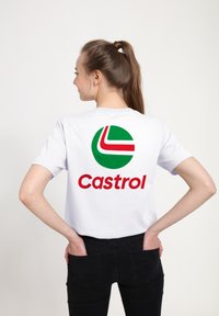 Bílý bavlněný tričko s motivem zeleného kruhového loga s červenými a bílými akcenty a textem "Castrol" tučným červeným písmem na zadní straně.