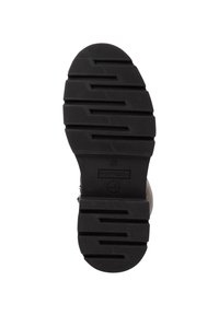 Suela de bota de goma negra con un patrón de tachuelas que presenta surcos horizontales y verticales para tracción y durabilidad. Taco aplanado con ligera curvatura.