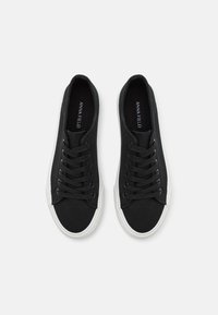 Schwarze Canvas-Sneaker mit sechs Ösen, schwarzen Schnürsenkeln und einer weißen Gummisohle. Das Innere ist mit dem Markennamen 'ANNA FIELD' in Weiß bedruckt.