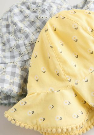 Kaks puuvillast kaabuga nokamütsi: üks kollane valgete lillemustrite ja pom-pom äärisega, teine hall ruuduline valgete tikandustega lilledega.