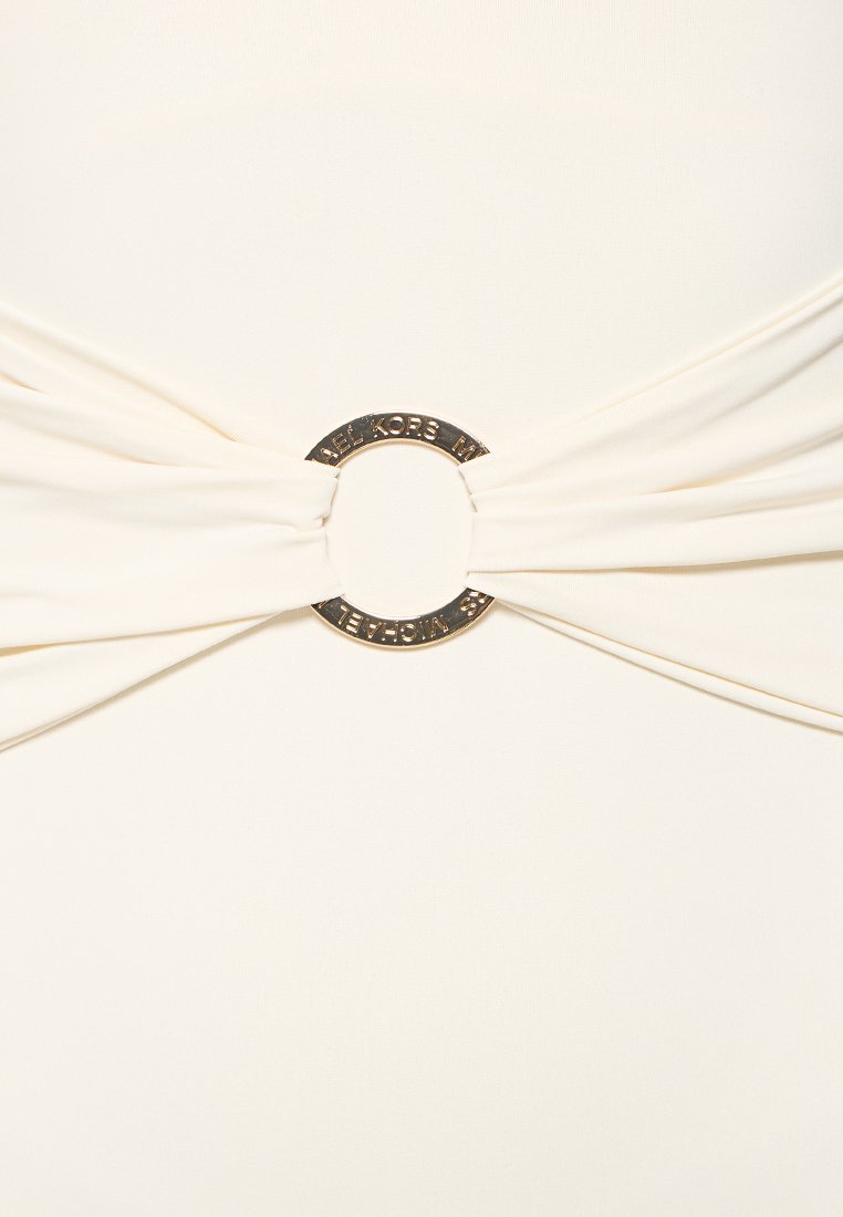 Beige Stoff, der gerafft und durch einen goldenen, sowie auf beiden Seiten mit "MICHAEL KORS" gravierten, runden Ring gezogen ist.