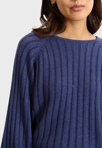 Navy-blau gestreifter Pullover aus weichem Strickmaterial, mit weiter Ausschnitt und geripptem Struktur, sowie fallenden Schulternähten.