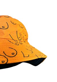 Orange tygkeps med en upprepande svart linjetecknad mönster. Kepsen har en strukturerad design och en böjd skärm.