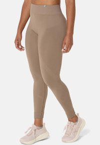 Beige high-waisted leggings with ribbed texture and seamless design, featuring angled pattern details and a snug fit at the ankles.