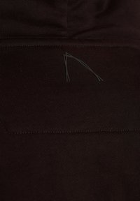 Tessuto atletico nero con una texture liscia. Presenta cuciture sottili e un piccolo logo curvo stampato in un colore scuro.