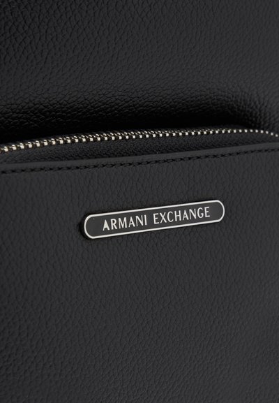 Черна текстурирана синтетична материя с цип. Разполага с метална плоча с логото "Armani Exchange". Гладка повърхност с фини детайли.