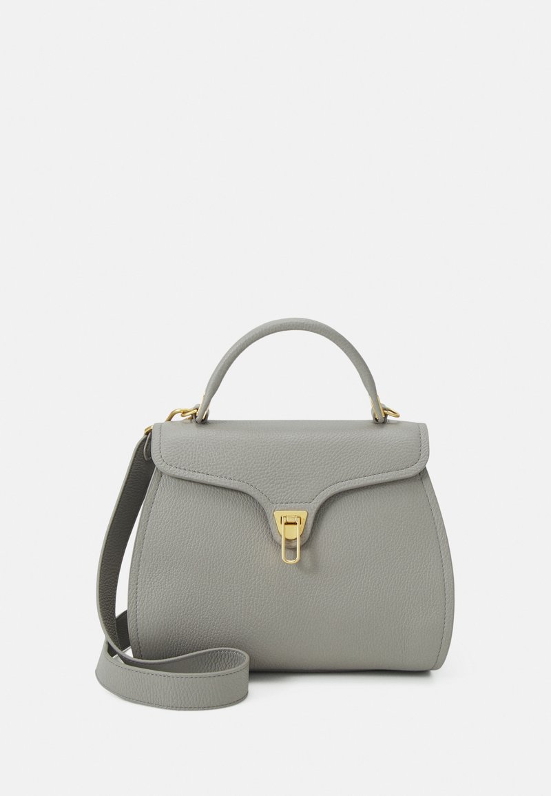 Sac à main en cuir gris avec poignée supérieure, rabat avant, fermoir doré et bandoulière amovible sur fond uni.