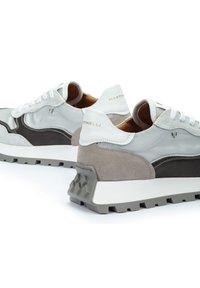 Zapatillas grises y blancas con tejido de malla, acentos de ante, una entresuela blanca gruesa y una suela exterior texturizada en gris. Nombre de la marca en el talón.