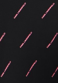 Tejido negro con un patrón repetido del texto "Karl Lagerfeld" en un vibrante color rosa, dispuesto diagonalmente sobre la superficie.