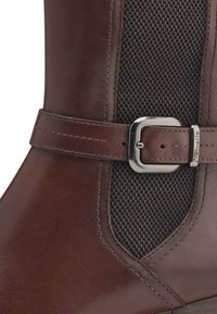 Bottines en cuir marron avec un panneau en maille texturée marron, un accent en boucle en métal argenté et des détails de couture précis.