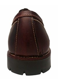 Zapato de cuero marrón con tacón redondeado, costuras visibles y una suela de goma negra texturizada. La vista trasera resalta los detalles de las costuras.