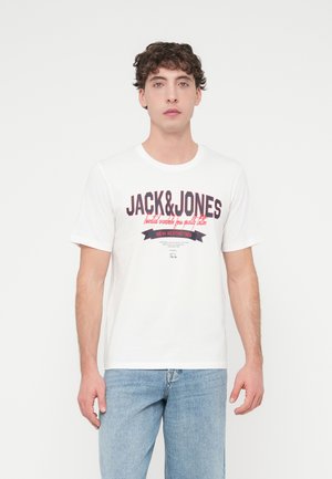 Wit katoenen T-shirt met een groot zwart-wit rood "JACK&JONES" logo met een lintdetail. Gecombineerd met lichtblauwe spijkerbroek.