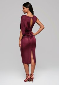 Robe midi bourgogne avec des manches drapées, des détails froncés sur les côtés, une ouverture au dos et une fente sur le côté. Texture lisse et silhouette ajustée.