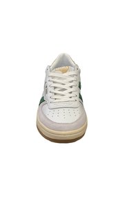 White sneaker with green accents, smooth leather upper, rubber sole, lace-up front, perforated toe box, and beige detailing on the sole.