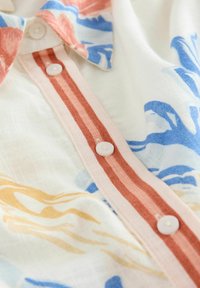 Lichte, gestreepte blouse met een kraag, witte knopen en strepen in pastelkleuren: roze, oranje, blauw en geel.