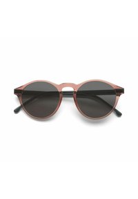 Gafas de sol redondas con un marco translúcido rosa, lentes oscuros y varillas negras. Sin logotipos visibles ni elementos adicionales.