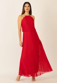 Rotes plissiertes Maxikleid mit Halterneck und goldenen Kettenakzenten, das eine fließende Silhouette und strukturierte Stoff bietet.