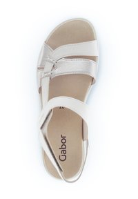 Light beige sandal with a soft leather upper. Features cross-strap design, cushioned footbed, and flexible sole. Brand logo visible inside.