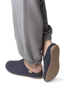 Dark blue woolen slippers with a rounded toe and open back, featuring a textured rubber sole with small colorful specks and a brand tag.
