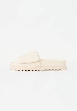 Sandal de slide bege com um upper texturizado apresentando bordados florais, uma tira larga e uma sola plana e estriada para melhor aderência.