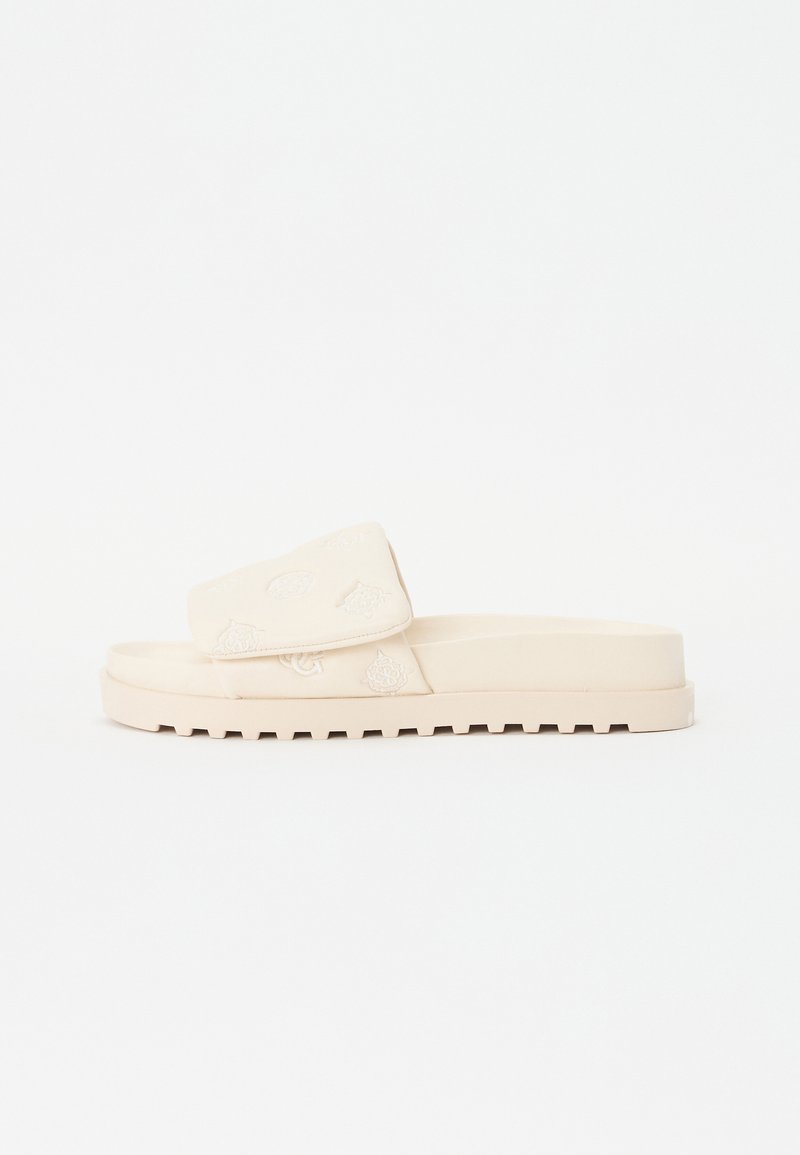 Sandale à glissière beige avec un dessus texturé ornée de broderies florales, une large sangle et une semelle plate à nervures pour une meilleure adhérence.