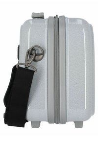 Valigia rigida con una superficie argentata lucida, cerniera grigia e una tracolla nera regolabile attaccata da un clip metallico. Forma compatta.