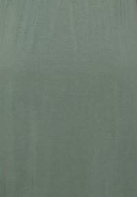 Tecido verde, leve, com uma textura suave. Design simples, brilho subtil e um topo elástico que reúne para um ajuste descontraído. Sem padrões ou acessórios.