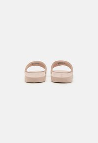 Sandales en caoutchouc roses avec une semelle texturée et un dos ouvert. Elles présentent deux larges sangles sur le pied pour un maintien et un confort optimaux.