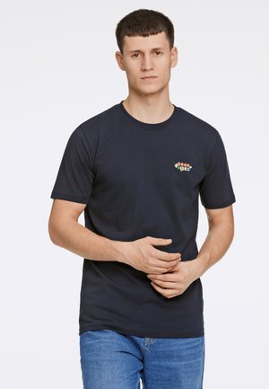 Marineblaue Baumwoll-T-Shirt mit kurzen Ärmeln, das ein mehrfarbiges, gesticktes Logo "Good Vibes" auf der linken Brust trägt.