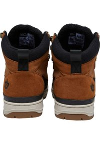 Chaussures montantes en suède brun et textile noir avec une semelle intermédiaire blanche, présentant des coutures décoratives, des tirants et un logo en forme de feuille à l'arrière.