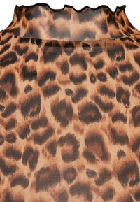 Prozirna tkanina s uzorkom leopardove boje koja sadrži smeđe i crne točke na svijetlo smeđoj podlozi; detalj volana na izrezu.