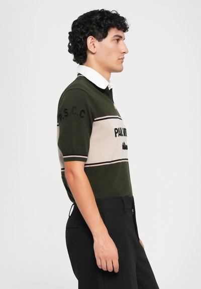 Dunkelgrünes Polohemd mit kurzen Ärmeln und beigen horizontalen Streifen, mit gesticktem Text, einem Kragen und weichem Material.