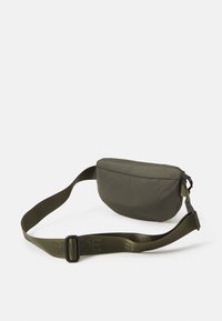 Borsa a vita in tessuto verde oliva con chiusura con zip, forma curva e tracolla regolabile; presenta un design elegante e minimalista.