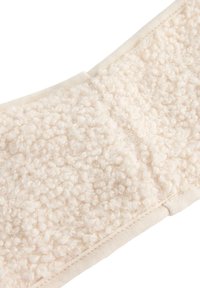 Tessuto di colore crema con una superficie fuzzy e texture. Bordato con un bordo beige liscio, presenta morbidi pom pom arrotondati disseminati nel materiale.