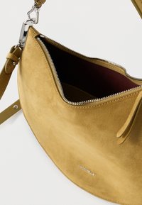 Suede shoulder bag in mustard yellow with a silver zipper. Features a smooth texture and a dark red interior, including a matching strap.