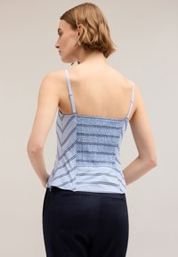 Top senza maniche di colore azzurro chiaro con schiena arricciata e strisce orizzontali blu scuro. Presenta spalline sottili regolabili e una forma morbida.