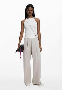 Valge varrukateta top diagonaalse rihmaga, koos helebeeži plisseeritud laiade pükstega. Aksessuaarideks tume sidur ja värvilised hiired.