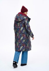 Zateplený kabát s květinovým vzorem v tmavých barvách, se skládací kapucí a kontrastní bordó podšívkou. V kombinaci se světle modrými širokými džíny.