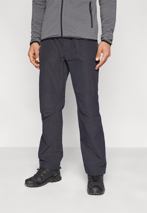 Black outdoor pants with a smooth texture, featuring two side pockets, reinforced seams, and fitted ankle openings, paired with black shoes.