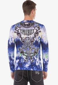 Langärmliges blaues Batikshirt mit schwarzem grafischem Design, mit Schädelmotiv und dem Markennamen "CIPO & BAXX", der prominent auf dem Rücken angezeigt wird.
