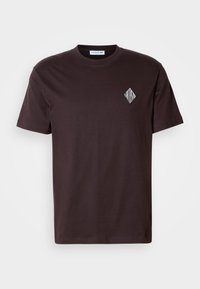Czarny bawełniany t-shirt z okrągłym dekoltem, krótkimi rękawami oraz białym logo w kształcie diamentu na lewej stronie klatki piersiowej. Prosty design, bez wzorów.
