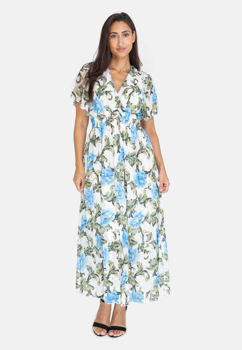 Blommig maxiklänning i vitt med blå blommor och gröna blad. Korta svävande ärmar, midja med insnitt och flödande kjol. Svarta öppna sandaler.