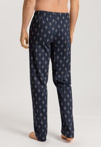 Marineblauwe pyjamabroek met een elastische tailleband. Voorzien van een geometrisch ruitpatroon in rood en wit tegen een donkere achtergrond. Zacht materiaal.