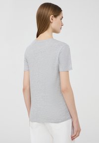 T-shirt grigio a maniche corte con scollatura rotonda, realizzato in un materiale morbido e texturizzato, dotato di un orlo curvo e una vestibilità casual.