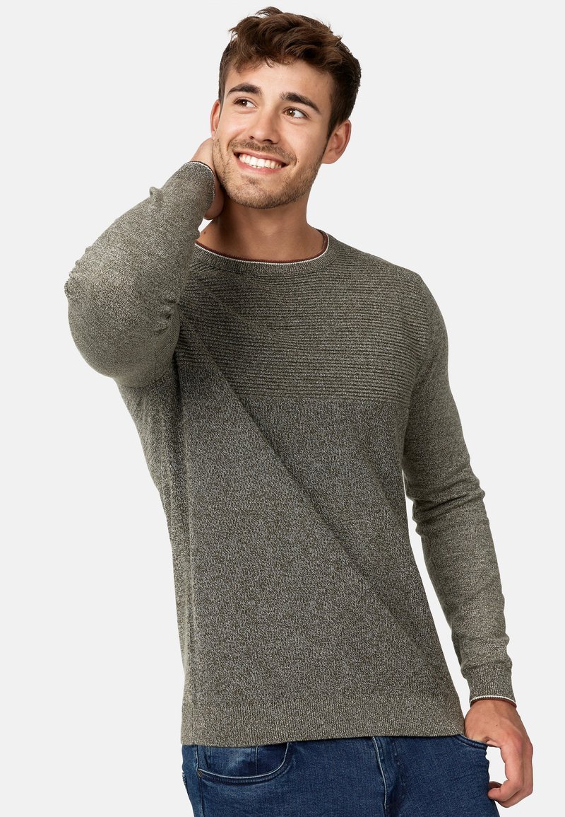 Grå tekstureret sweater med rund hals, der har en ribbet øverste sektion og lange ærmer. Bæres med blå jeans, der viser en afslappet pasform.