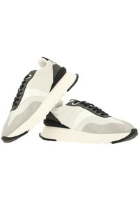 Baskets grises et blanches avec une tige texturée, des accents noirs et une semelle blanche épaisse. Présentent un design à lacets et une pointe arrondie.