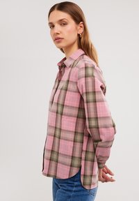 Camicia a quadri nei toni del rosa, verde e marrone. Design con bottoni, maniche lunghe, orlo curvo e taschino sul petto. Materiale in cotone.