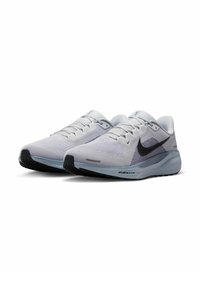 Buty Nike z siateczkową cholewką w białych i szarych odcieniach, z charakterystycznym czarnym swooshem, teksturowanymi akcentami oraz amortyzowaną podeszwą dla lepszego wsparcia.